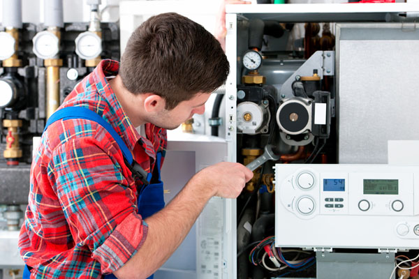 Heating technician repairing boiler controls in Pomona