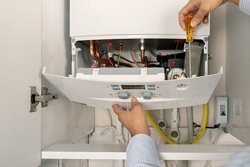 Heating technician repairing a residential boiler in Pomona