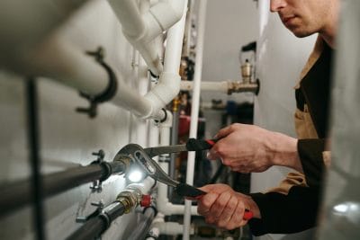 Technician inspecting commercial plumbing pipes in Pomona