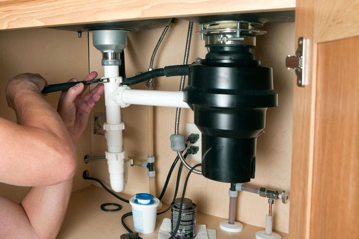 Plumber repairing a garbage disposal in Pomona