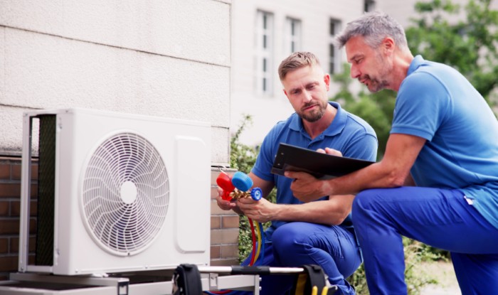 HVAC technicians installing an outdoor air conditioning unit in Pomona