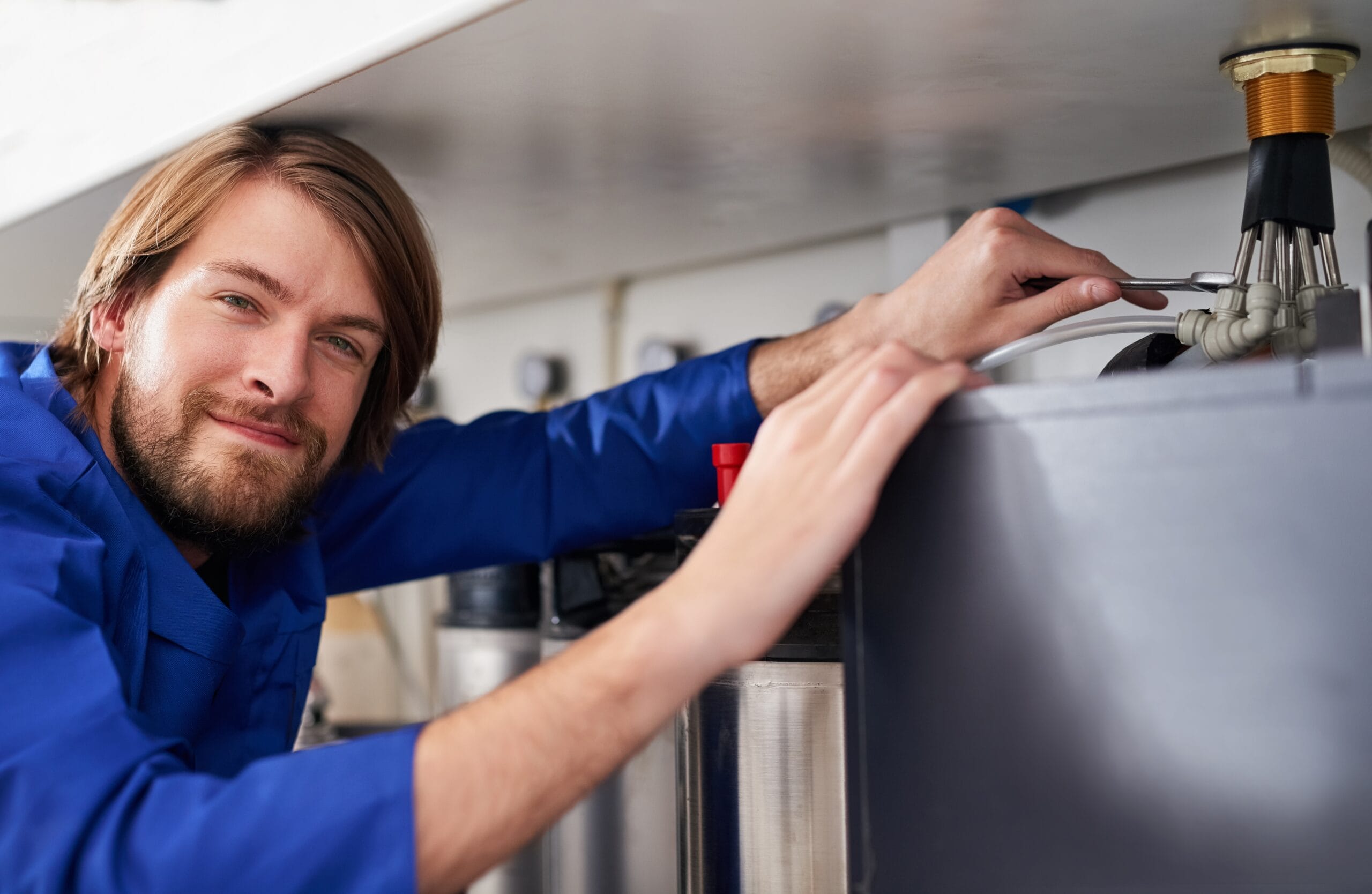 Technician servicing a residential water heater tank in Pomona
